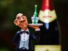 Figur eines Butlers, der ein Tablet mit Sekt und Gläsern trägt