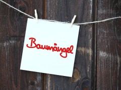 Zettel mit dem Text »Baumängel« vor Holzbrettern