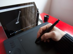 Hand mit Stylus auf einem Wacom-Grafiktablett und Anzeige auf dem Surface-Tablet